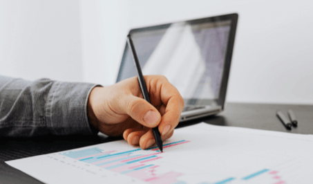 A person writing on a paper with graphs